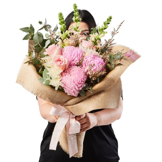 Pink Hessian Bouquet with pink chrysanthemums roses and eucalyptus wrapped in rustic hessian and held by a florist for same day delivery flowers