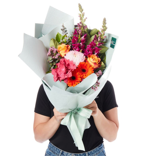 Vibrant Bloom Bouquet with bright pink orange and red blooms wrapped in soft white paper for birthday flowers and same day delivery flowers